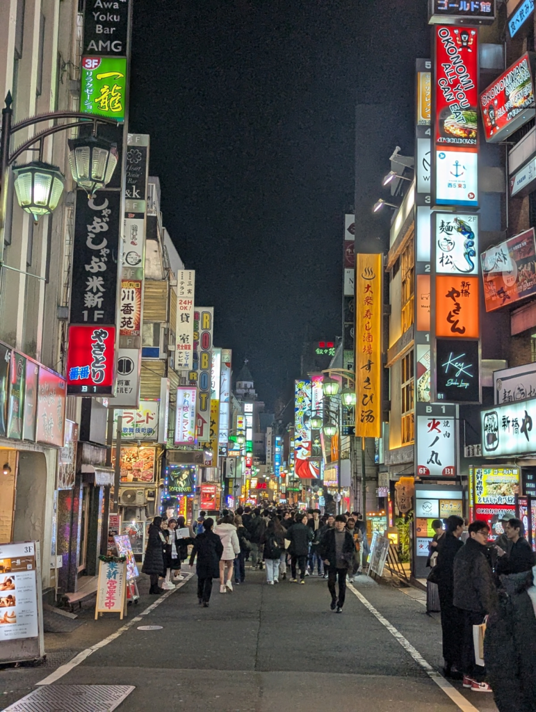 Le quartier animé de Shinjuku à Tokyo, avec ses gratte-ciel, ses néons et ses restaurants typiques japonais.